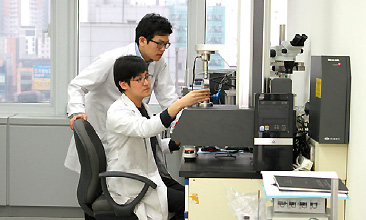 의료용 임플란트 융합연구실 - 2명의 연구원이 현미경 앞에서 실험하는 사진